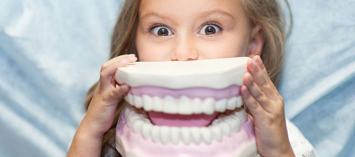 kinder-zahnmedizin-berlin-kudamm1 Ein Kind hält sich den Gipsabdruck eines Gebisses vor den Mund